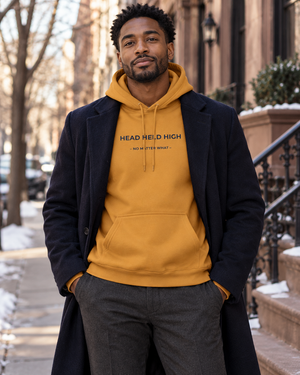 Hoodie HEAD HELD HIGH Mutu Likolo, coloris mustard, porté en ville en automne-hiver — mise en scène numérique.