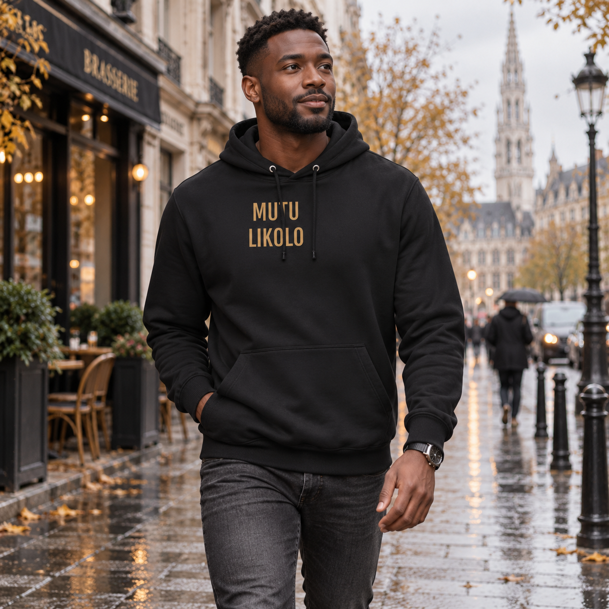 Homme portant le hoodie noir Mutu Likolo dans une rue urbaine en automne